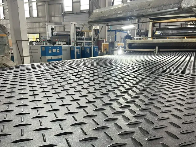 Textured black panel on rollers in front of production equipment