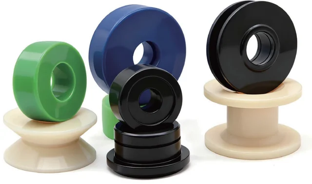 Green, blue, black and light-coloured machined bushings and flanged shaft sleeves