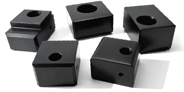 Five black machined sliding blocks with bores and stepped profiles