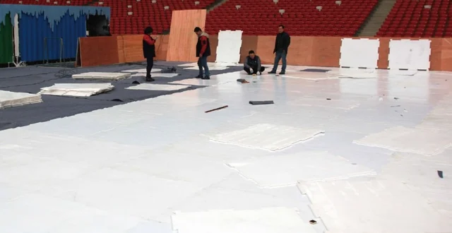 White synthetic ice panels being laid in an indoor venue